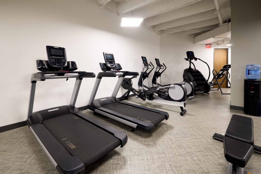 Row of cardio exercise machines, including treadmills, ellipiticals and a stair mill.