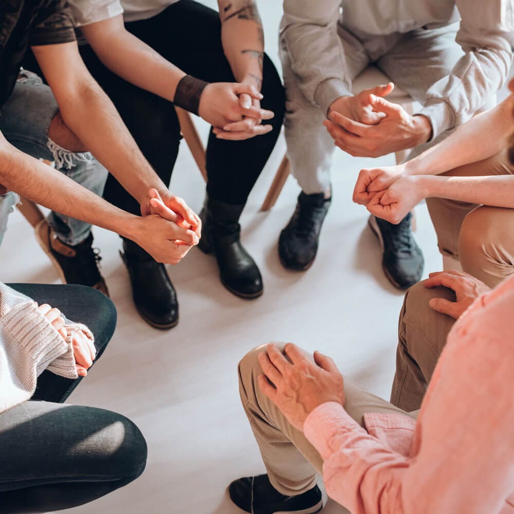 A diverse group of individuals seated in a circle, engaged in conversation and sharing ideas.