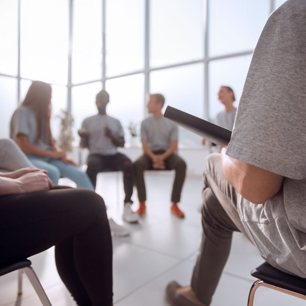 A diverse group of individuals engaged in conversation while seated in chairs, fostering a lively discussion.